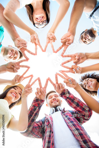 Unity and connection of people. Topview of multi ethnic students friends, putting their fingers together, wearing casual clothes, otdoors on a sunny day. Conception of successful teambuilding