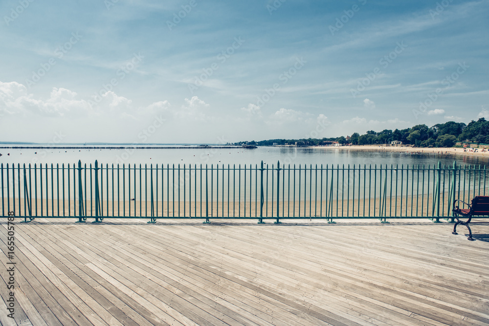 Empty ocean beach boardwalk pier at hot summer day against blue sky