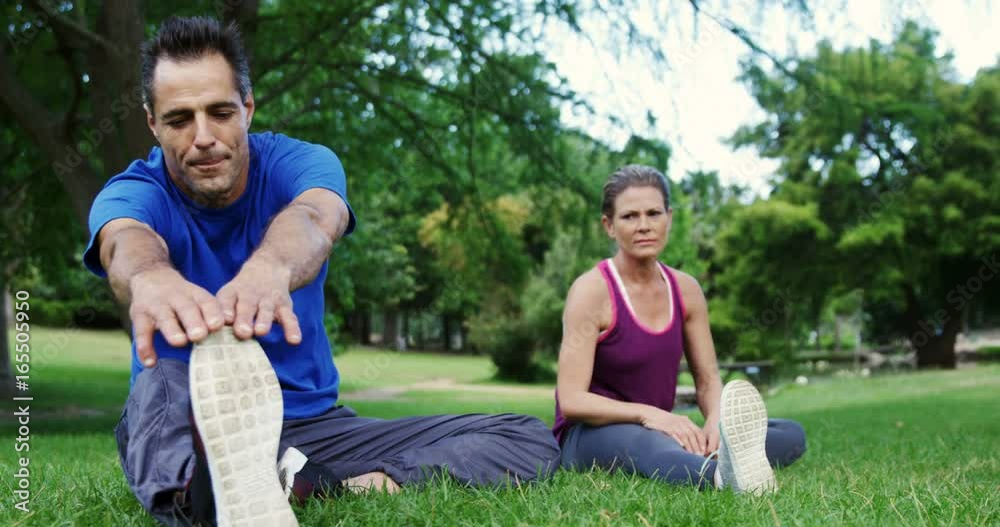 Mature couple performing stretching exercise in the park Mature couple performing stretching exercise in the park