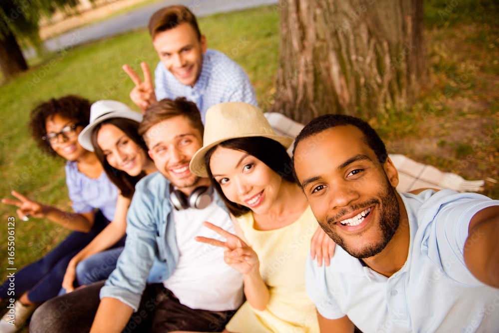 Selfie time! Six international students with beaming smiles are posing for selfie shot, that african handsome guy is taking, outside school building. Gathered, cheerful, smart and successful youth