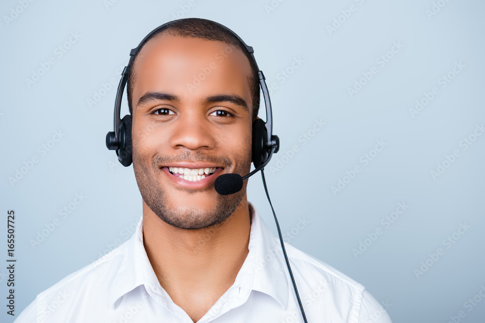 Young cheerful african guy call center worker in headset on a pure light background, wearing headset and smart white shirt, smiling Young cheerful african guy call center worker in headset on a pure light background, wearing headset and smart white shirt, smiling