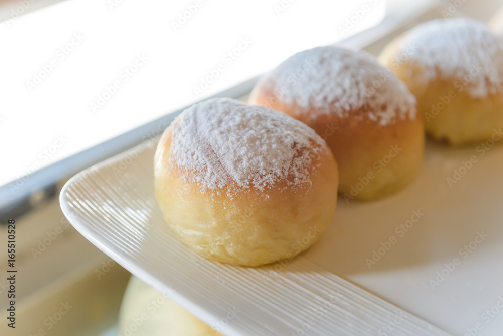 Homemade fresh breads with powdered sugar on top in white plate