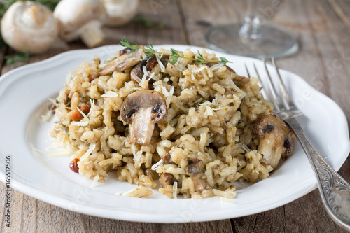 Mushroom risotto on white plate on wooden table. Closeup view