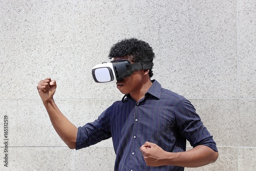 Young man wearing virtual reality goggles flexing muscles