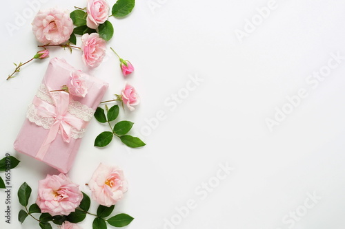 Fototapeta Naklejka Na Ścianę i Meble -  Bouquet of beautiful pink roses and gift in pink packing on white  background.Top view.Copy space
