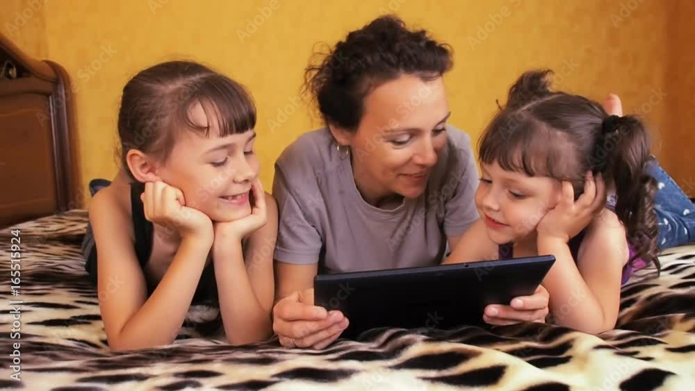 Mom and children laugh at the tablet. Family with a tablet. Mom and children laugh at the tablet. Family with a tablet.