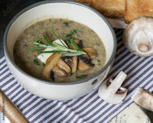 Creamy mushroom soup with root vegetables and almonds decorated with fresh parsley and rosemary.