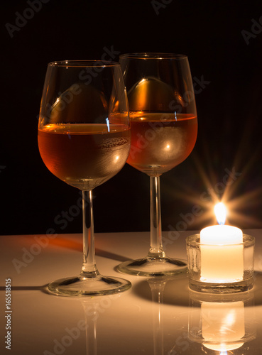 Two glasses of wine highlighted by a candle light