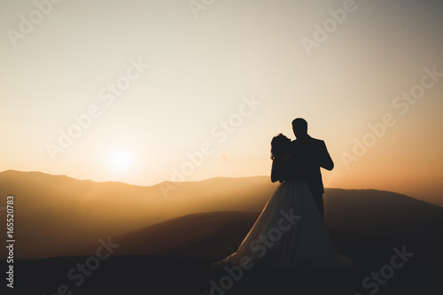 Happy beautiful wedding couple bride and groom at wedding day outdoors on the mountains rock. Happy marriage couple outdoors on nature, soft sunny lights