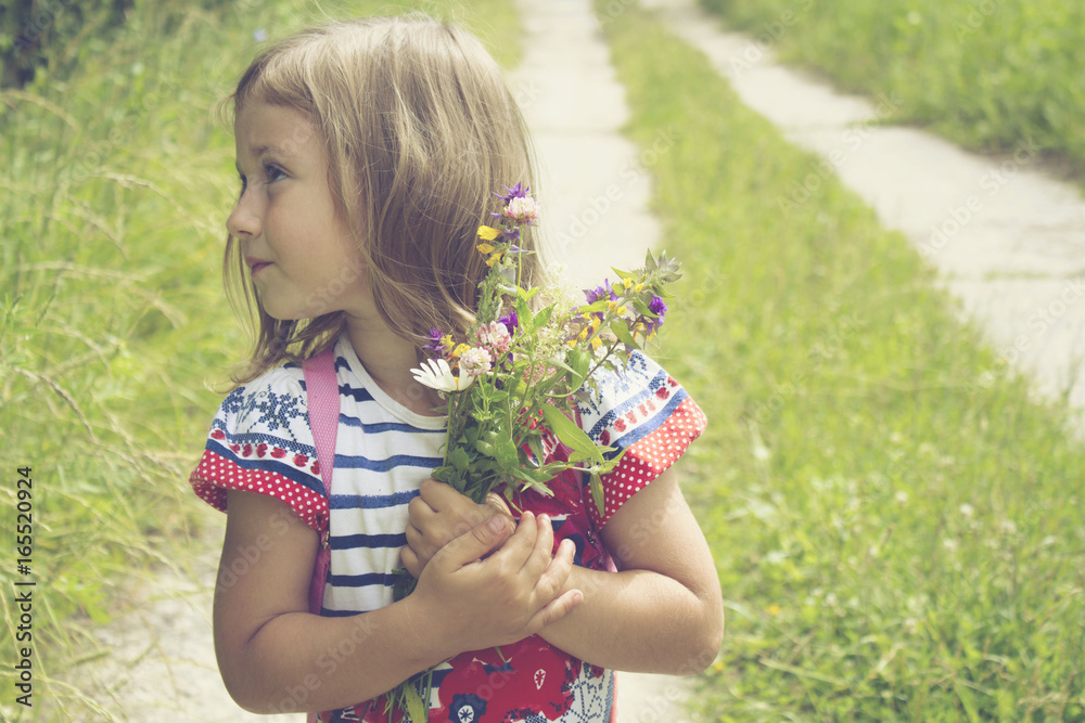 Cute little girl walking on the road with bouquet of flowers Cute little girl walking on the road with bouquet of flowers