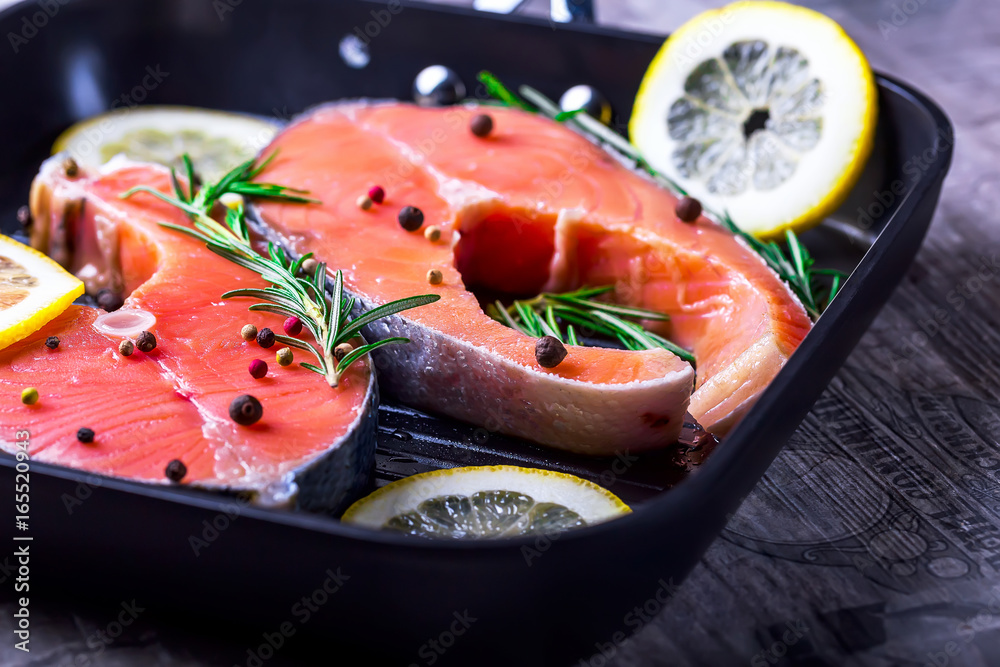 Salmon steaks in a grill pan with lemon, herbs and spices