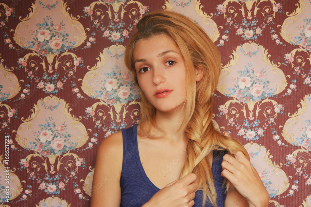 Fototapeta premium young Woman in blue shirt doing braid on blonde hair