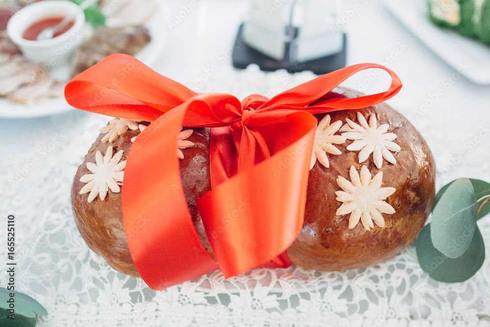 The bread with red bow stands on the wedding table The bread with red bow stands on the wedding table