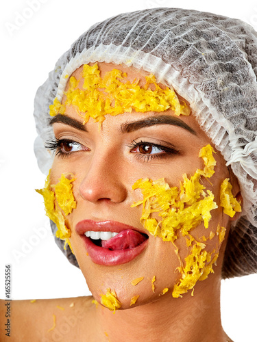 Fototapeta Naklejka Na Ścianę i Meble -  Facial mask from fresh fruits for woman. Girl in medical hat bit slices of kiwi and hold plate with fruit salad. Crushed orange on face. Cosmetic masks with natural ingredients.