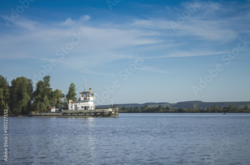A Russian ship sails along the river under a blue sky with white clouds.