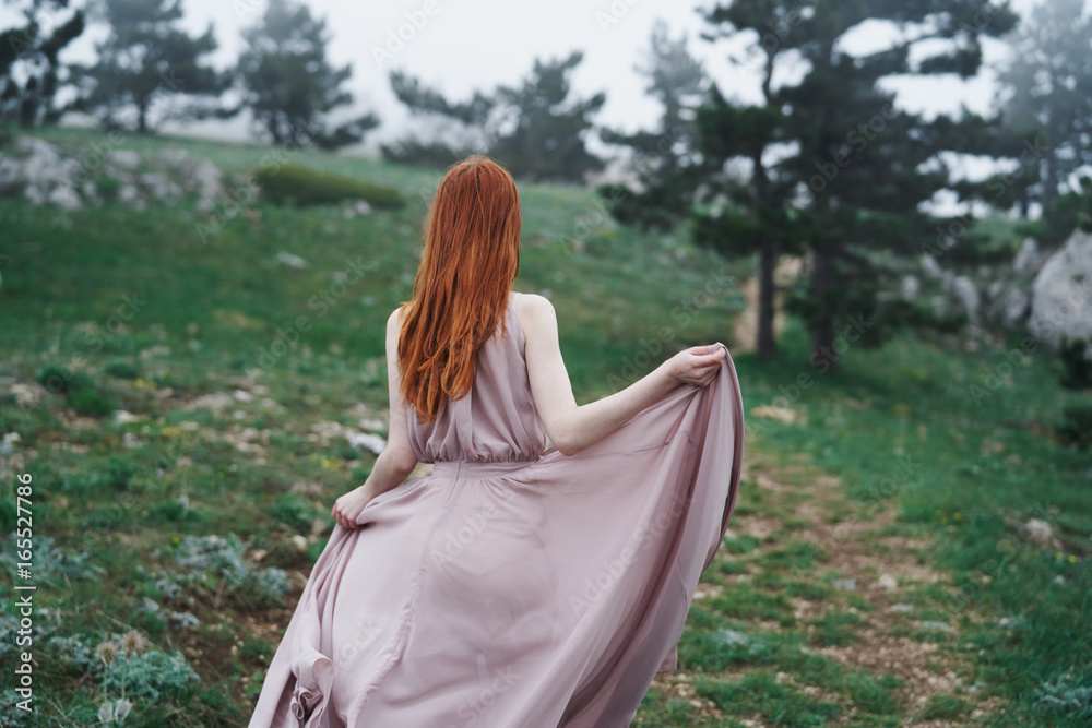 Beautiful young woman in a long dress walking in the mountains outdoors Beautiful young woman in a long dress walking in the mountains outdoors