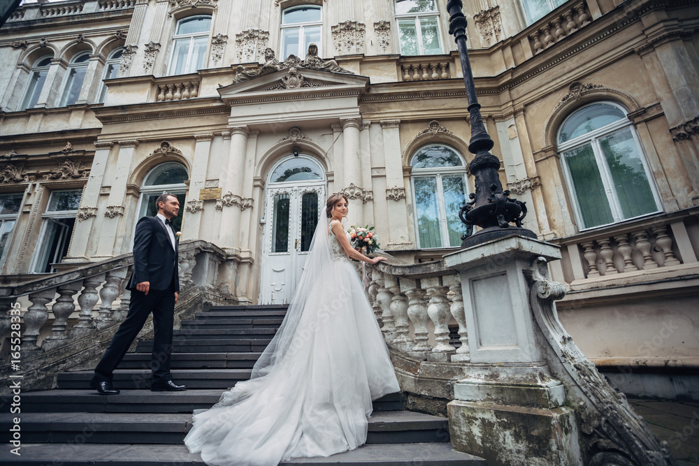Stunning bride and groom pose on the footsteps before an old house