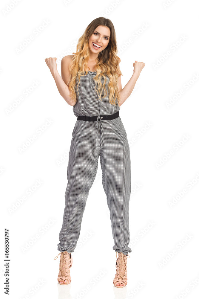 Smiling Young Woman In Jumpsuit And High Heels Clenches His Fists Smiling Young Woman In Jumpsuit And High Heels Clenches His Fists