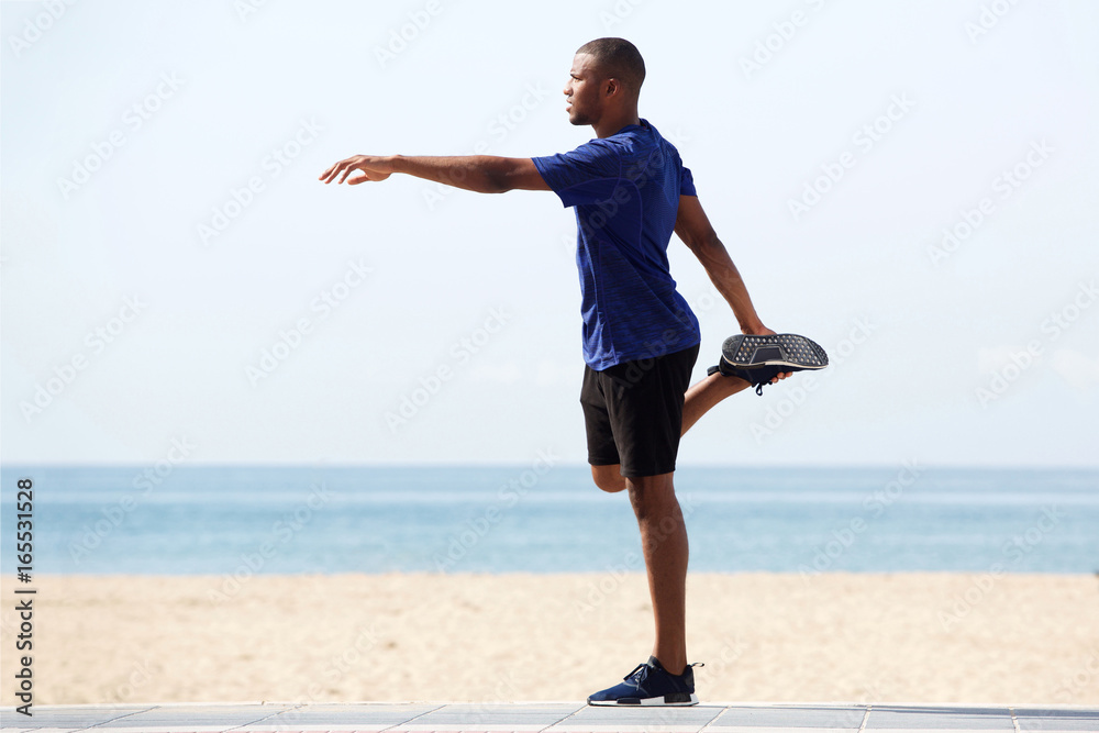Fit young african man doing warm up exercise on beach Fit young african man doing warm up exercise on beach