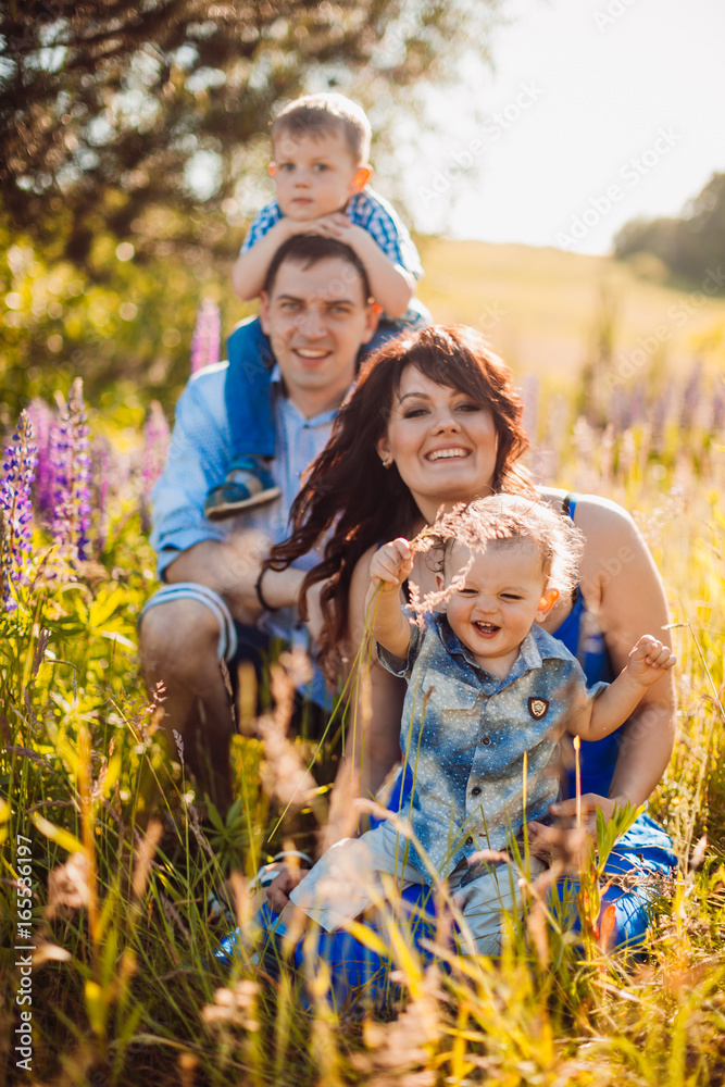 Obraz premium Happy family poses on the field in a sunny weather