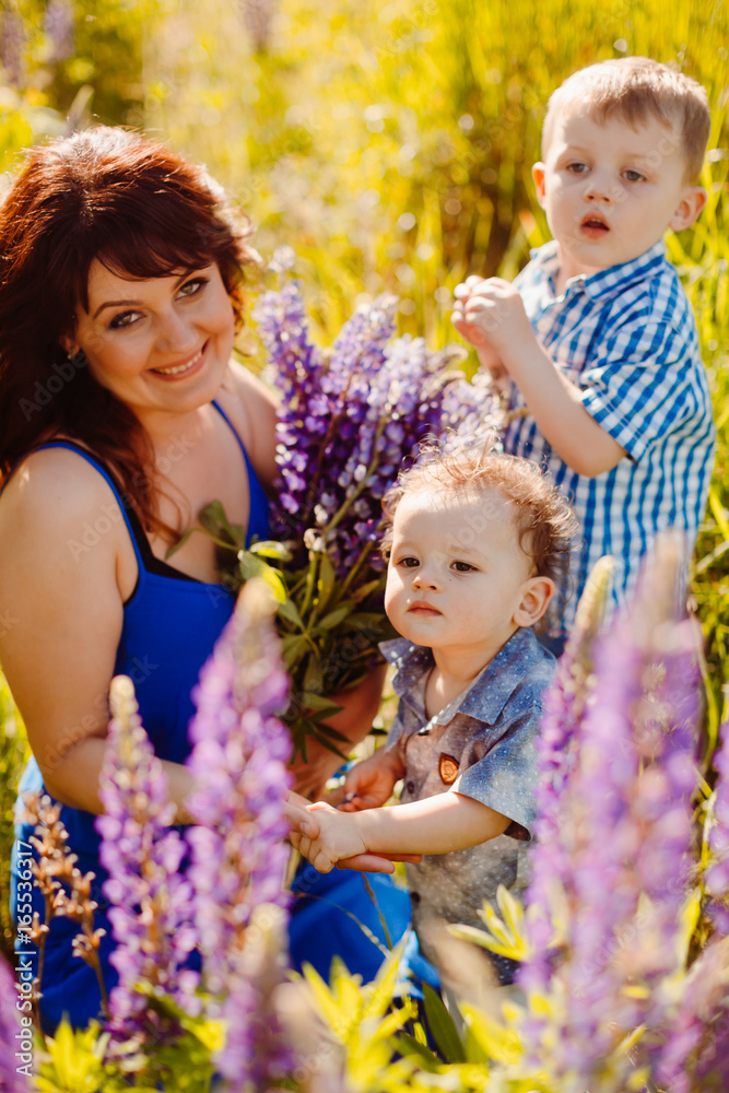 Mother with bouquet of lavander sits on the field with her sons Mother with bouquet of lavander sits on the field with her sons