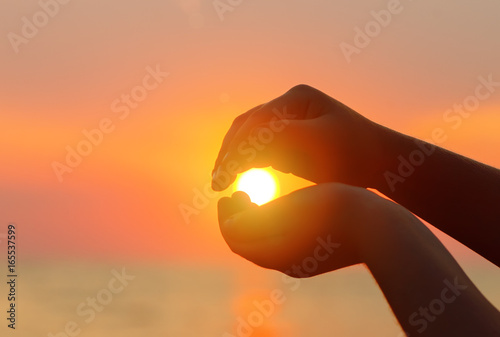 Sunset over the sea. The sun in a child's hand.