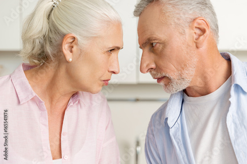 Angry mature man standing near mature serious woman