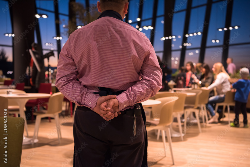 waiter standing with hands behind his back