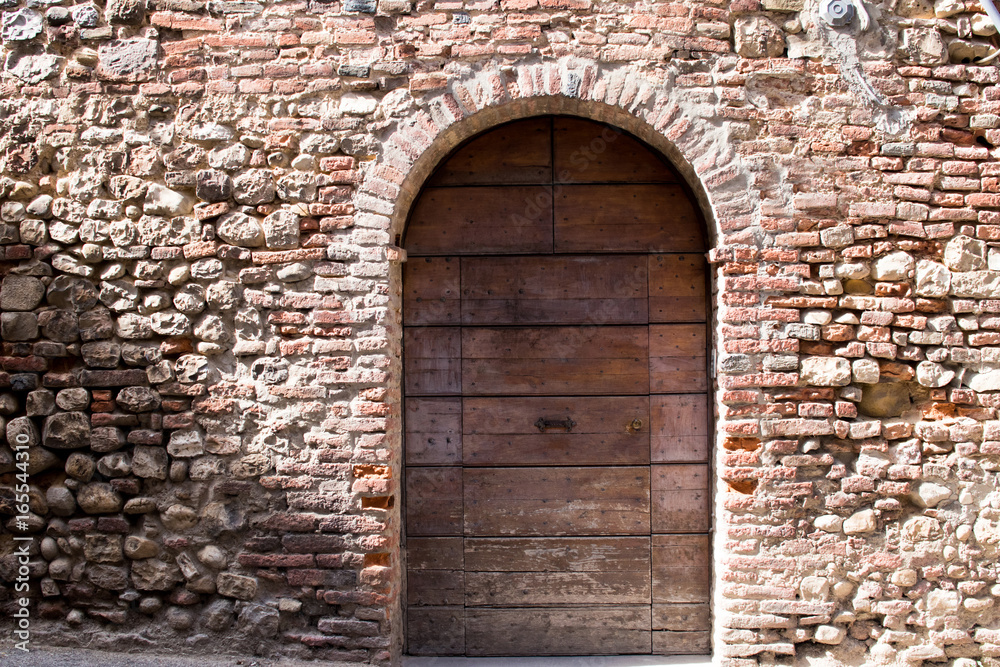 Ancient typical Italian house facade with brown door and brick wall. Holidays in Italy, Tuscany and Umbria
