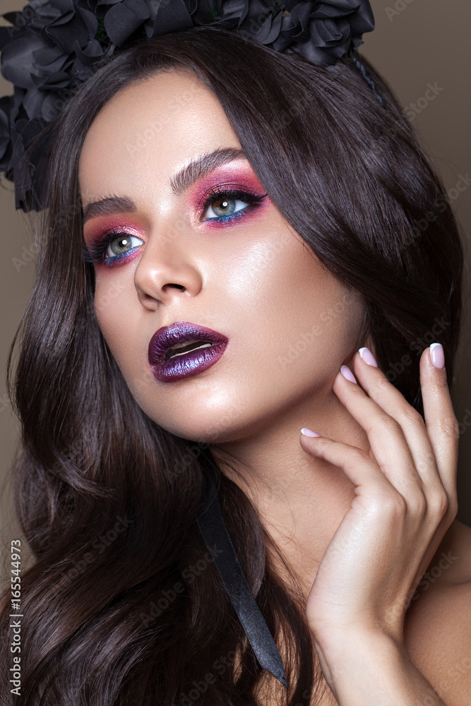 Fototapeta premium Beautiful young model with fashion make up, perfect skin, black flowers on the head. Trendy dark lips.