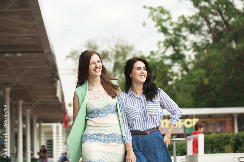 Two happy women walking in the summer park