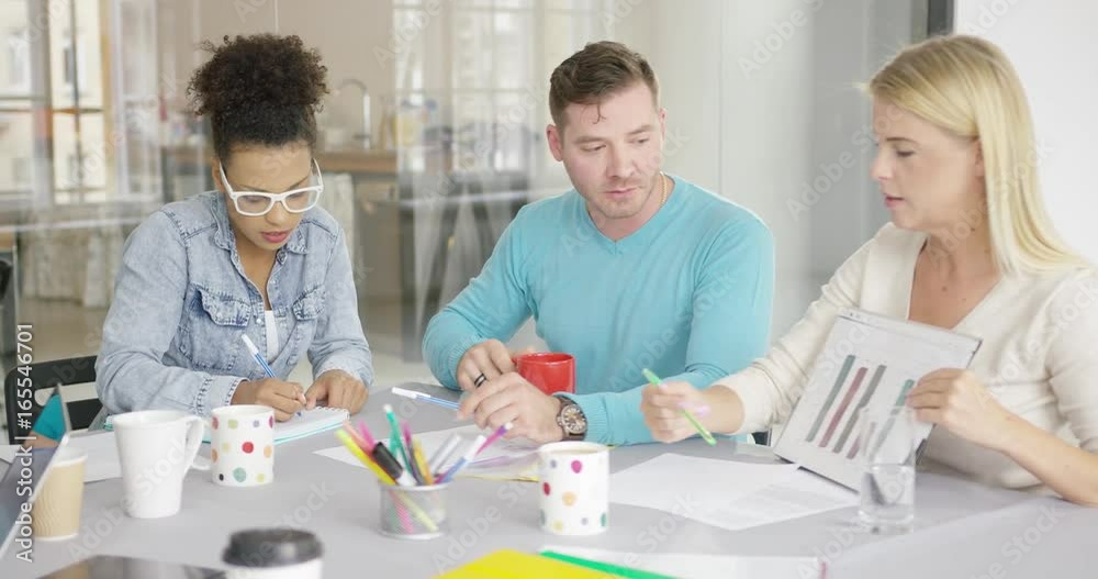 Group of young people concentrated on work with papers and documents while sitting at table in office. Group of young people concentrated on work with papers and documents while sitting at table in office.