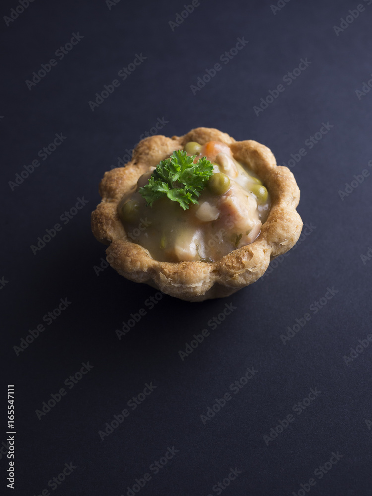 Savory Danish tartlet (tarteletter) made from puff pastry, filled with a creamy chicken, asparagus and carrot sauce. Isolated on black background