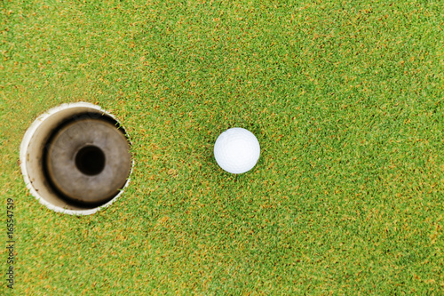Golf hole and golf ball on green grass on golf course