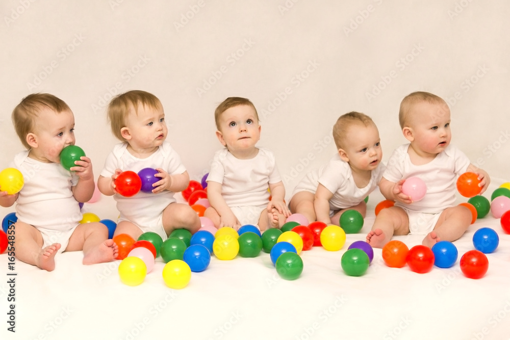 Five cute babies sitting among colorful balls. Party of newborns. Five cute babies sitting among colorful balls. Party of newborns.