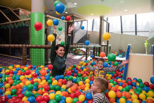 Young mom with her kids in a children's playroom photo