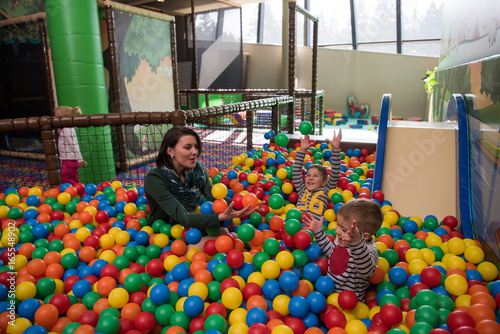 Young mom with her kids in a children's playroom photo