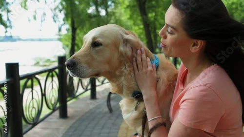 Loving young woman resting in the park with her dog