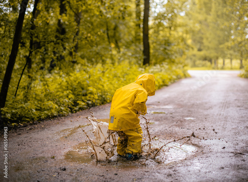Bild auf Leinwand Little girl jumping fun in a dirty puddle