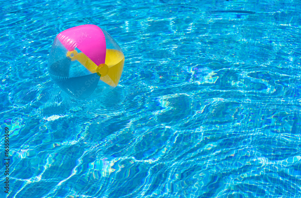 Colorful inflatable ball floating in blue swimming pool water