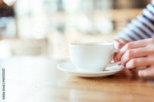 cropped shot of female hands holding cup of coffee on saucer