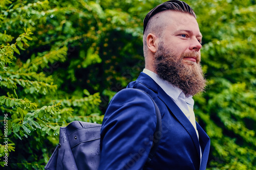 Bearded hipster over green bush background.