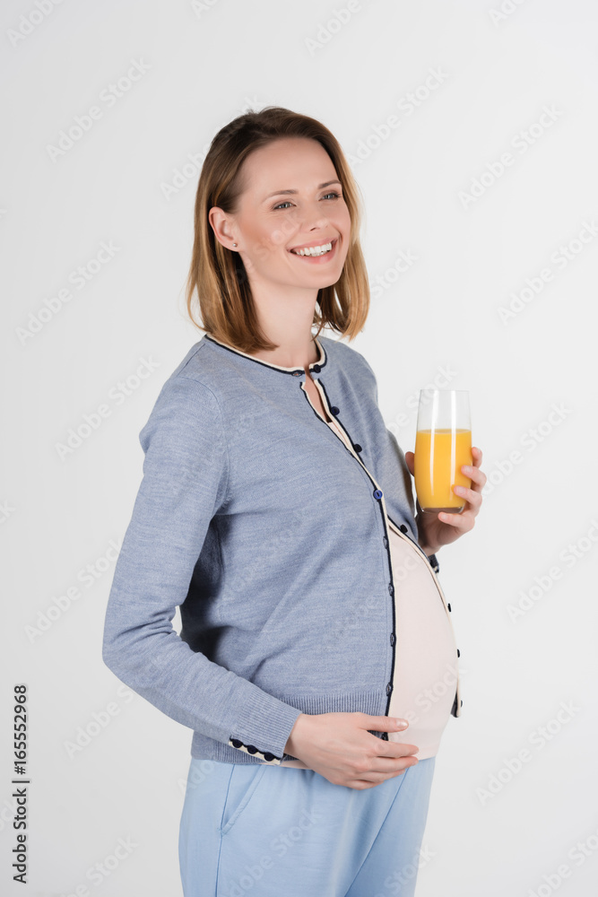portrait of young pregnant woman posing with glass of juice in studio isolated on grey portrait of young pregnant woman posing with glass of juice in studio isolated on grey