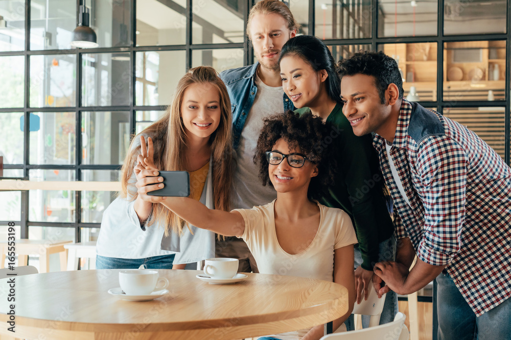 Young happy multiethnic friends taking selfie in cafe Young happy multiethnic friends taking selfie in cafe