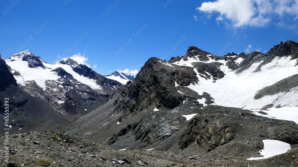schwarze Felsen mit weißen Schneefeldern im sonnigen Silvretta vor blauem Himmel