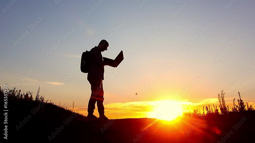 Silhouette of business man with laptop working on the field at sunset time. Concept freelancer, performing tasks, anger from failure and throwing a laptop. Silhouette of business man with laptop working on the field at sunset time. Concept freelancer, performing tasks, anger from failure and throwing a laptop.