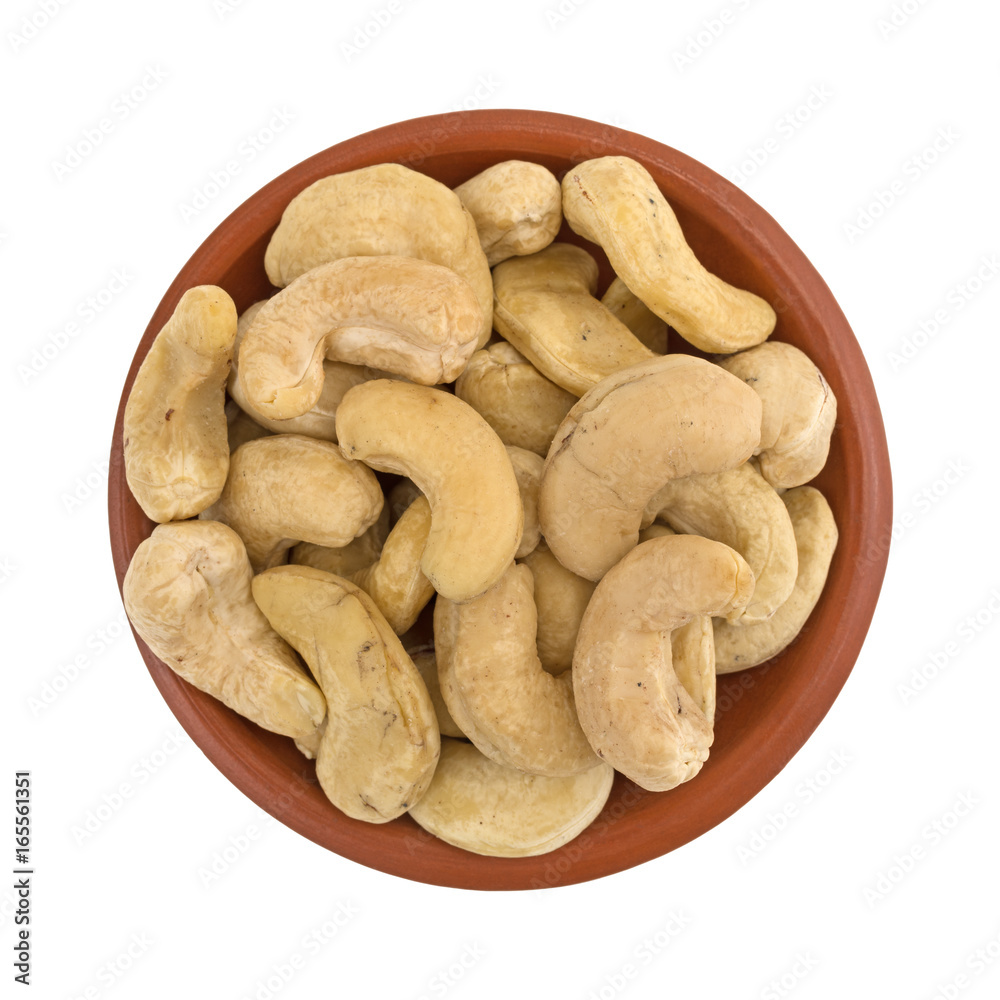 Top view of raw cashews in a small red clay bowl isolated on a white background. Top view of raw cashews in a small red clay bowl isolated on a white background.
