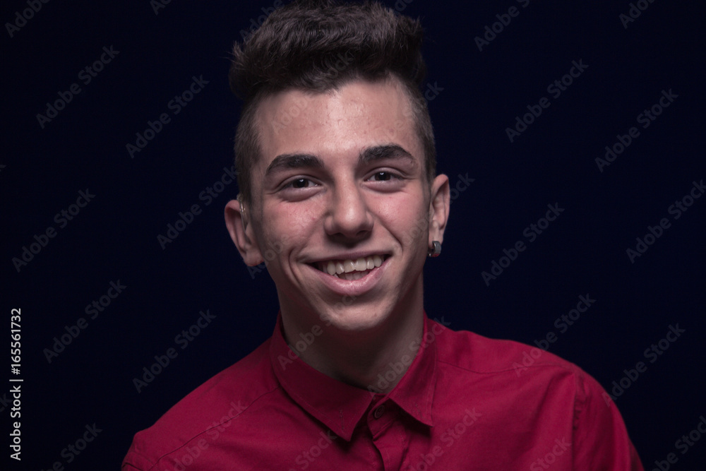 Obraz premium one teenager boy, red shirt, Caucasian, dark background, looking to camera, smiling