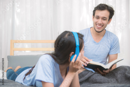 Obraz na plátně Couple relaxing in bedroom listening to music and reading a book at home