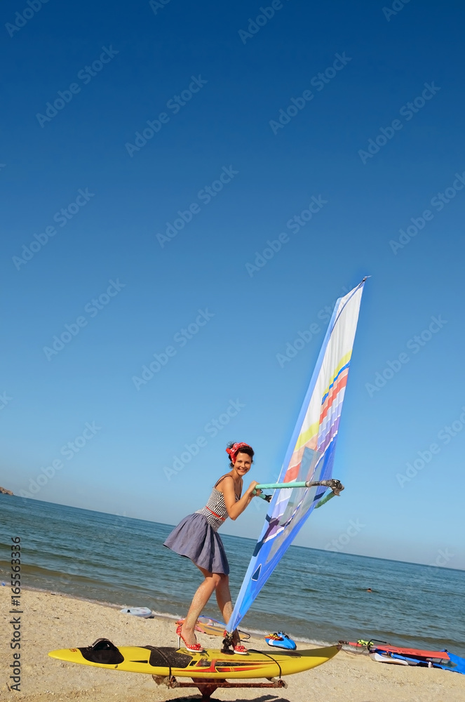 Naklejka premium A girl at a windsurfing school learns to ride a windsurf board. Sea. Pin an.